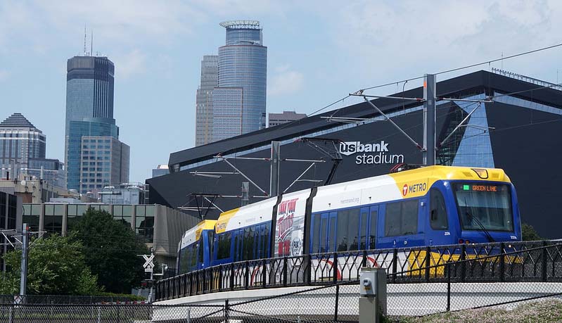 Green line light rail crossing a bridge with downtown Minneapolis in the background.